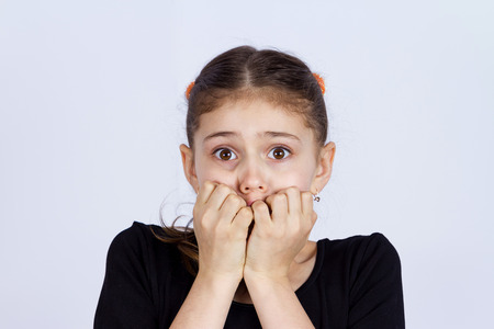 Closeup portrait young little girl biting her finger nailsの写真素材