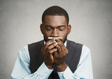 Closeup portrait, headshot, young handsome business man, corporate executive, funny looking guy, craving cigarette, tobacco, isolated black grey background. Bad, dangerous human health habits conceptの写真素材