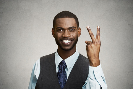 Closeup portrait, headshot young man, student holding up peace, victory, two sign , isolated black background. Positive human emotion, facial expressions, symbols, attitude communication. Life successの写真素材