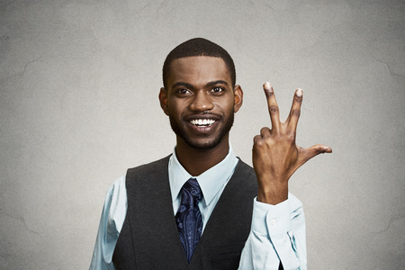 Closeup portrait young happy, confident, handsome business man giving a three times fingers sign gesture with hands, isolated black grey background. Positive emotion facial expression feeling, symbolsの写真素材