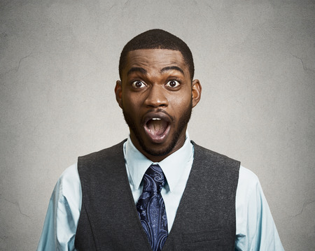 Closeup portrait happy young man, wide open mouth looking shocked, surprised in full disbelief isolated black grey background. Positive human emotions, facial expressions, feeling, attitude, reactionの写真素材