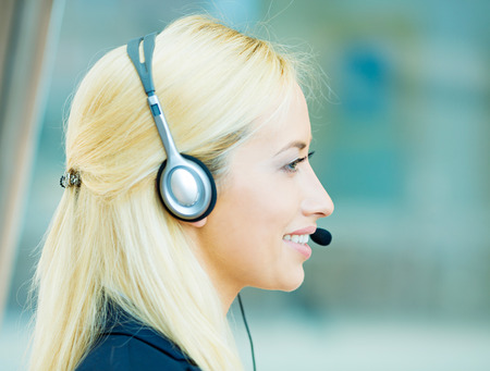 Closeup portrait, headshot young happy successful business woman, customer service representative, call centre worker, operator, support staff speaking with head set isolated background office windowsの写真素材