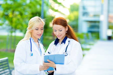 Closeup portrait friendly, happy, smiling female doctors, healthcare professionals isolated outdoors hospital background. Patient visit. Health care reform. Positive human face expression, emotionの写真素材