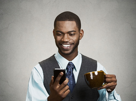 Closeup portrait happy, smiling business man reading good news on smart phoneの写真素材