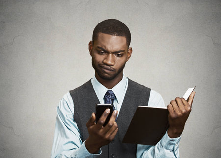 Closeup portrait confused, skeptical business man, executive reading news on smart phoneの写真素材