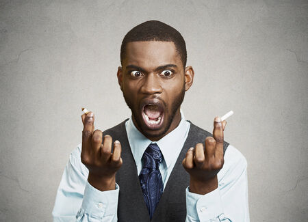 Closeup portrait, headshot, young, unhappy, angry business man, corporate executive finally broke cigarette, says no to smoking isolated black background. Life style changes. Human face expressionsの写真素材