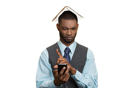 Closeup portrait upset, angry business man, funny looking corporate executive reading e-mail on smart phone, book over head isolated white background.の写真素材