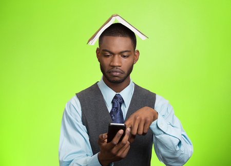 Closeup portrait serious business man, executive reading replying to message on smart phone holding mobile, book over head isolated green background. の写真素材