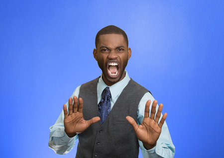 Closeup portrait furious angry annoyed displeased young man raising hands up to say no stop right there isolated blue background. Negative human emotion facial expression sign symbol body languageの写真素材