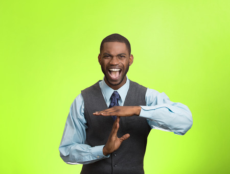 Closeup portrait stressed angry young business man showing time out gesture with hands, isolated green background. Negative human emotions, facial expressions, sign, symbols, body language, attitudeの写真素材