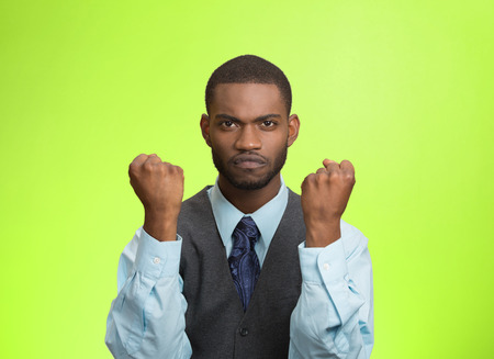 Closeup portrait angry cranky upset pissed off young man, worker business employee putting up fist ready to give knuckle sandwich isolated green background. Negative emotion, facial expression feelingの写真素材