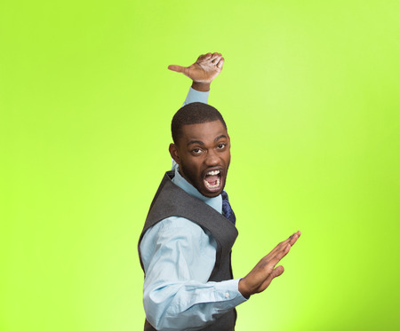 Closeup portrait angry mad furious, company man raising hands in air attack with karate chop isolated green background. Negative human emotion facial expression feeling, body language, signs, symbolsの写真素材