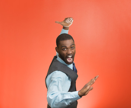 Closeup portrait angry mad furious, company man raising hands in air attack with karate chop isolated red background. Negative human emotion facial expression feeling, body language, signs, symbolsの写真素材