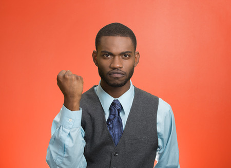 Closeup portrait angry cranky, upset, pissed off young man, worker, business employee putting up fist ready to give knuckle sandwich isolated red background. Negative emotion facial expression feelingの写真素材