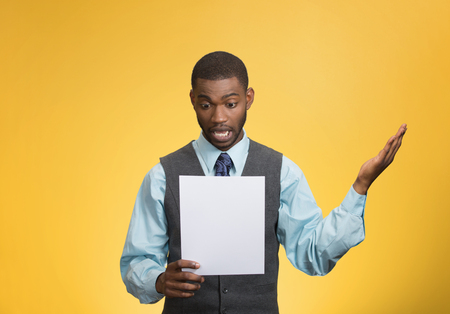 Closeup portrait shocked, funny looking young man, disgusted at monthly statement, test, application, results isolated yellow background. Negative human emotion, facial expression, feeling. Bad newsの写真素材