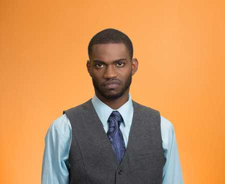 Closeup portrait angry, mad, annoyed, bitter, suspicious, business man, unhappy, looking at you, isolated orange background. Human emotion, face expression, attitude, interpersonal conflict resolutionの写真素材