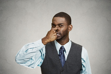 Closeup portrait young executive man, disgust on face, pinches his nose, something stinks, bad smell, situation isolated grey background. Negative emotion facial expression, perception body languageの写真素材