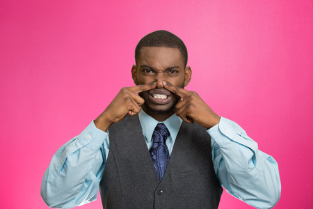 Closeup portrait young executive man, disgust on face, pinches his nose, something stinks, bad smell, situation isolated pink background. Negative emotion facial expression, perception body languageの写真素材