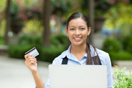 Closeup portrait happy young business woman smiling holding credit card and laptop for online oder, shopping concept isolated outdoors background  Positive facial expressions, emotionsの写真素材