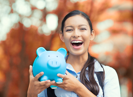 Closeup portrait happy, smiling business woman, bank employee holding piggy bank, isolated outdoors indian autumn background. Financial savings, banking concept. Positive emotions, face expressions Closeup portrait happy, smiling business woman, bank employee holding piggy bank, isolated outdoors indian autumn background. Financial savings, banking concept. Positive emotions, face expressions