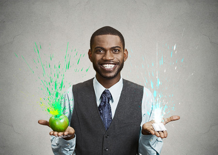 Closeup portrait young fit happy man holding green fresh apple in one hand, chewing gum in another, with colorful splashes coming out. Face expression, emotion. Fresh breath, good taste flavor conceptの写真素材