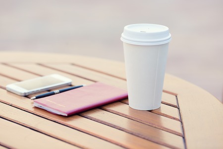 Closeup paper coffee cup, weekly organizer, planning book, smartphone, pen on table of city cafe, outside on sunny day. Life, accessories of corporate businesspersonの写真素材
