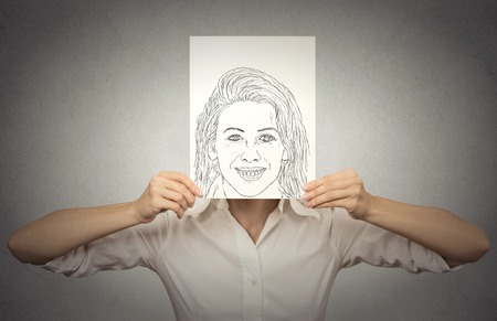 beautiful woman with happy self portrait in front of her face, hiding her true emotions, mood, isolated on grey wall background. Private life, identity conceptの写真素材