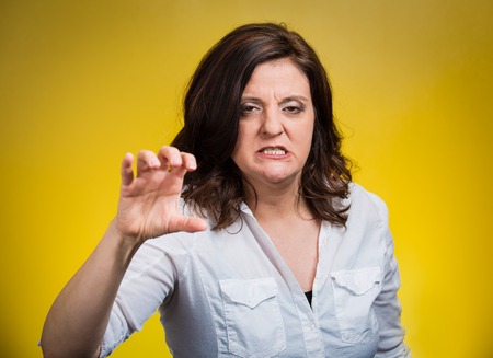 Closeup irritated stressed unhappy angry middle aged woman threatening someone with her claws nails isolated yellow background. Negative human emotion facial expression feeling reaction body languageの写真素材