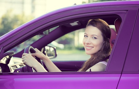 Portrait smiling, attractive happy woman, buckled up, driving, testing her new violet car, automobile, purchased at dealership, isolated street, city traffic background. Safe driving habits conceptの写真素材