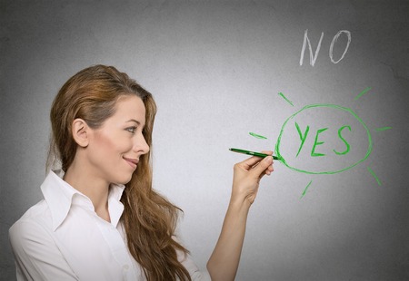 Woman circles with pen yes choice on blackboardの写真素材