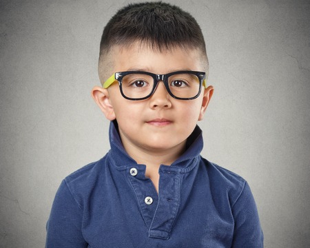 Portrait happy child with glasses on grey wall background. Face expressionsの写真素材