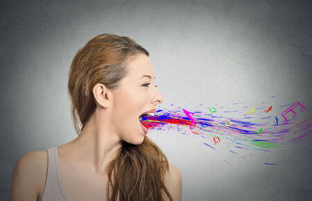 Side view portrait headshot woman young girl singing open mouth colorful splash abstract notes flying away isolated grey wall background. Human face expressions, emotions, feelingsの写真素材