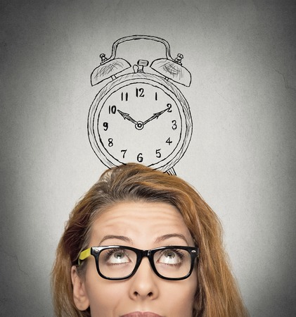 closeup headshot young business woman with alarm clock drawing sketch above her head, isolated grey wall background. Human face expressions, emotions. Time, punctuality, busy schedule concept closeup headshot young business woman with alarm clock drawing sketch above her head, isolated grey wall background. Human face expressions, emotions. Time, punctuality, busy schedule concept