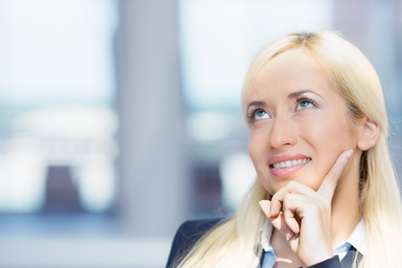 Closeup portrait charming, smiling joyful happy business woman looking upwards daydreaming something, thinking isolated background corporate office windows. Positive human emotions, facial expressionの写真素材
