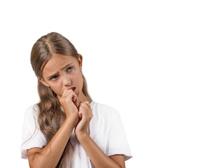 Closeup portrait teenager girl with finger in mouth, sucking thumb, biting fingernail in stress, clueless, isolated on white background. Negative emotion facial expression feeling. Body languageの写真素材