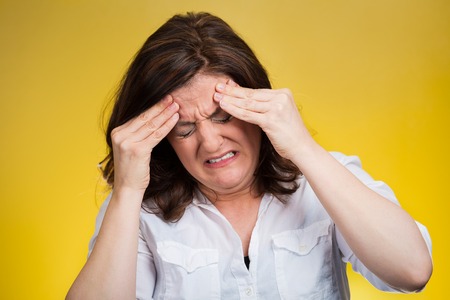 Stress headache. Closeup portrait stressed woman having many thoughts, worried about future, thinking isolated yellow background. Human face expressions, feelings, emotions, life perception, reactionの写真素材