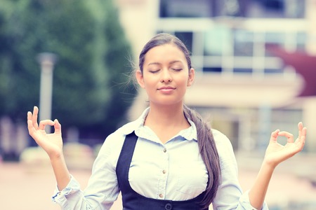 Portrait happy young business woman in blue shirt eyes closed hands raised in air relaxing meditating taking deep breathの写真素材