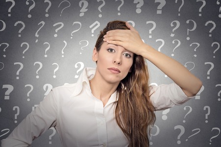 Portrait stressed woman with headache has many questions isolated grey wall background with question marks.の写真素材