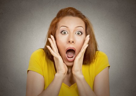 frightened shocked woman looking at camera isolated on grey wall background.