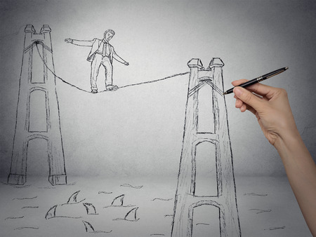 Businessman walking on a rope over sea filled with sharks, business competition concept. Sketch drawn by human handの写真素材
