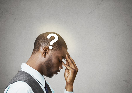 Side view portrait young puzzled business man thinking solving problem fingers on forehead looking down question mark over head isolated grey wall background copy space.の写真素材