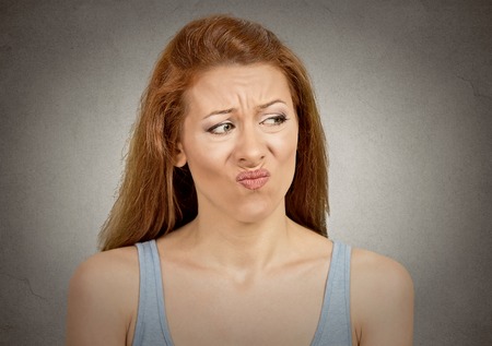 Upset disgusted woman with displeased face expression isolated on grey wall background. の写真素材