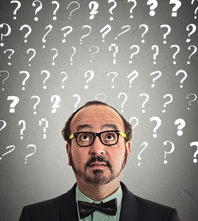 middle aged man with puzzled face expression and question marks above head looking up isolated grey wall background. の写真素材