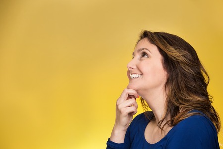 Side view profile portrait thoughtful happy woman smiling looking up daydreaming isolated over yellow background. Positive human face expressions, emotions, feelings, perceptionの写真素材
