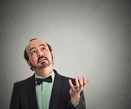 Closeup portrait  businessman looking up  arm out asking what's problem who cares so what isolated...