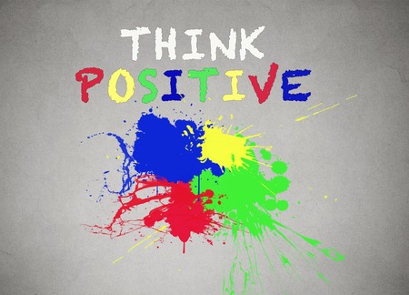 Green, blue, red, yellow splatter of paint isolated grey wall background, blackboard banner with colorful splashes think positive writing words on it. Positive life concept.の写真素材
