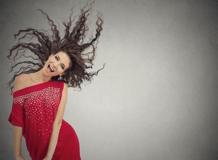 Studio shot young happy laughing playful woman posing in red dress isolated on grey wall  background with copy space. Positive emotion, face expressionの写真素材