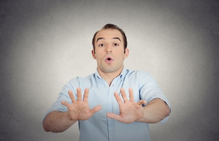 Closeup portrait helpless scared young man raising hand up to say no stop right there isolated grey wall background. Negative emotion facial expression feelings, signs symbols, body language reactionの写真素材