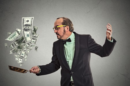 Middle age businessman juggling money dollar bills banknotes isolated on grey wall backgroundの写真素材