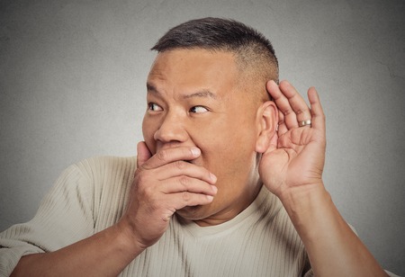 Headshot of man, hand to ear gesture trying secretly listen in on juicy gossip conversation news privacy violation, shocked by what he hears, isolated on grey background. Face expression, emotionの写真素材